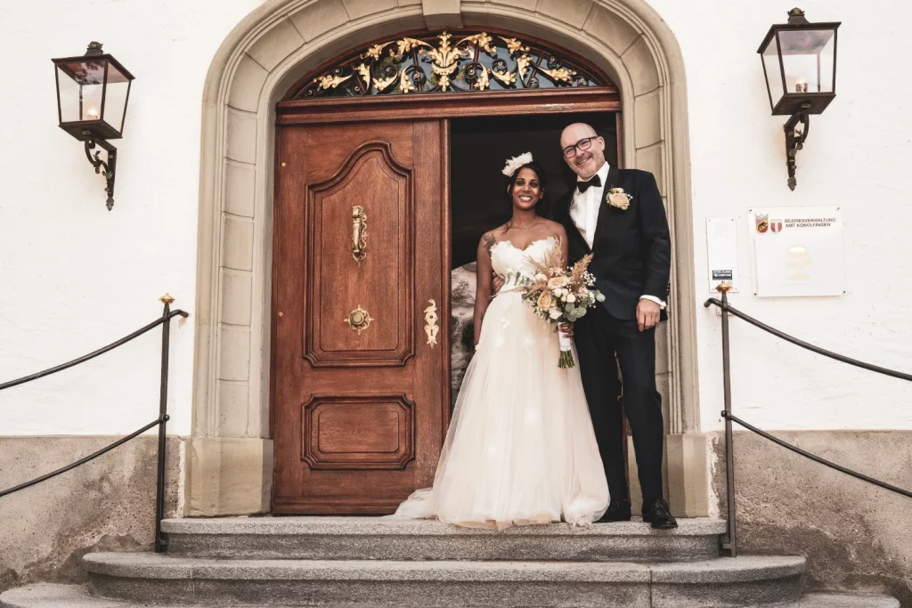Bride and groom in front of a historic door at the civil registry office – elegant wedding photo by hochzytfotograf.com